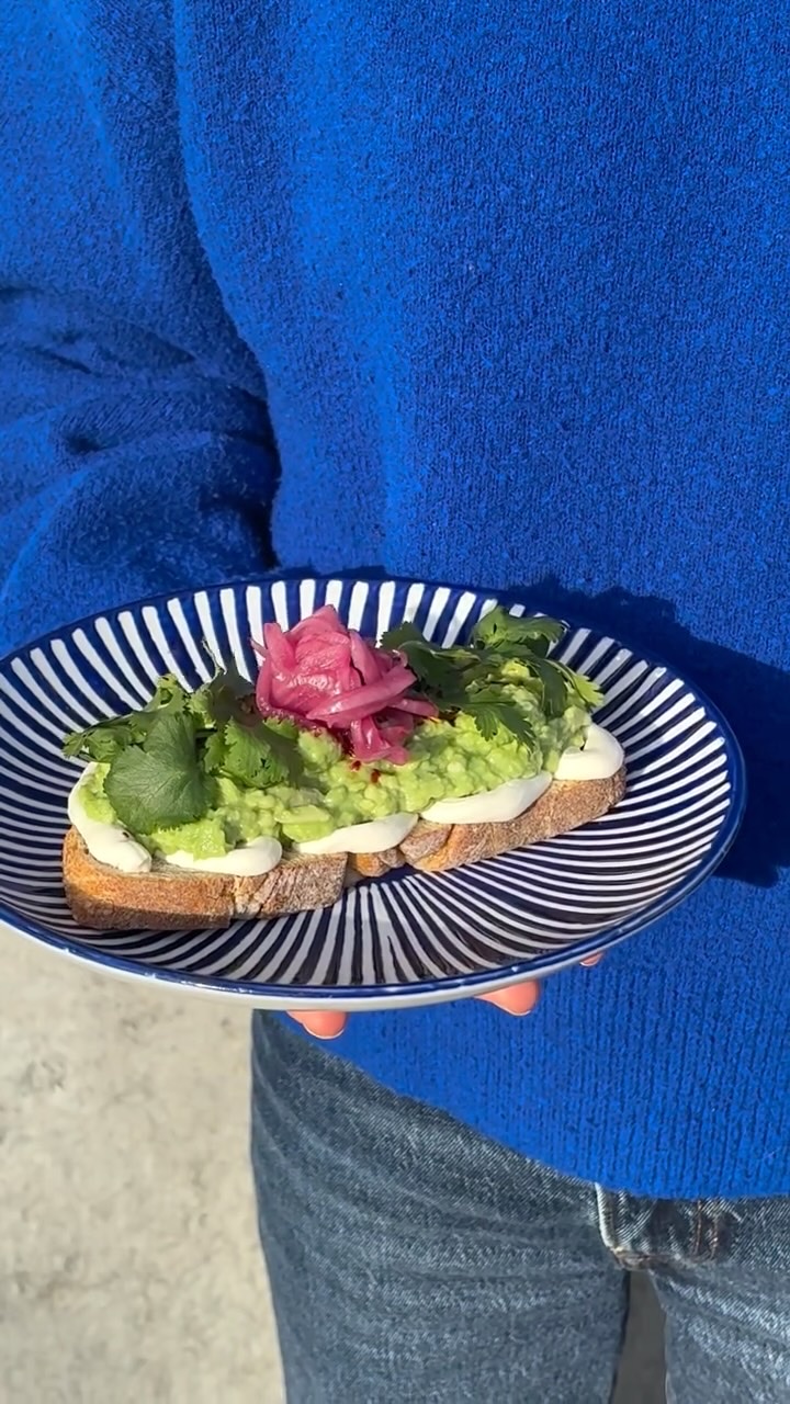 Avokadotoast med picklad rödlök och koriander på randig tallrik