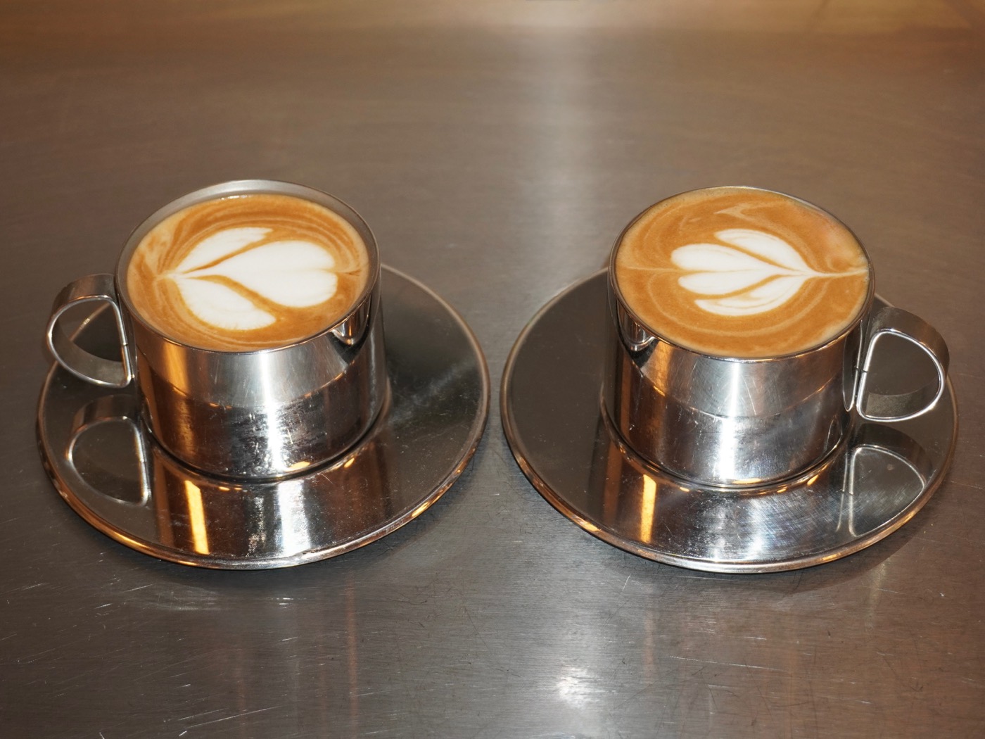 Två cortados med latte art i stålkoppar