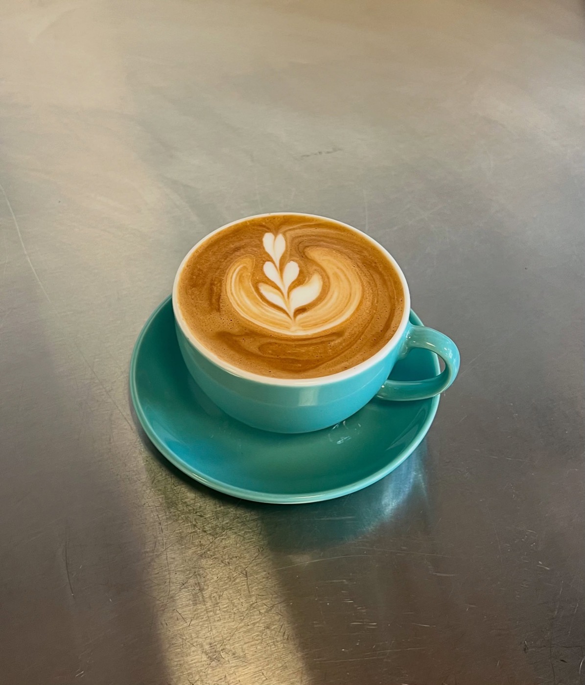 Latte med latte art i turkos kopp